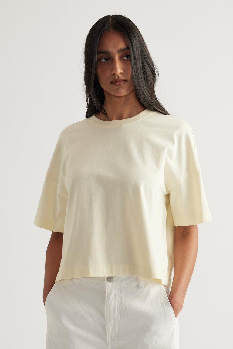 Woman wearing an off-white cropped boxy tee with short sleeves and a crew neck