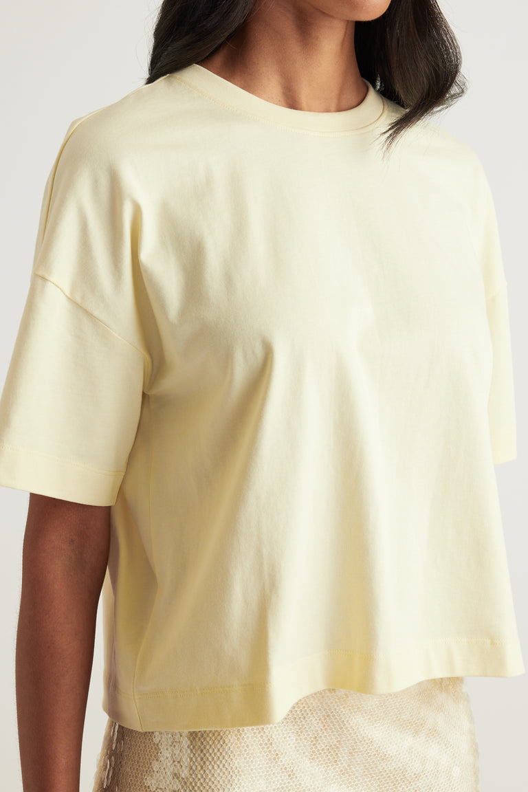 Woman wearing a pale yellow cropped boxy crew neck tee