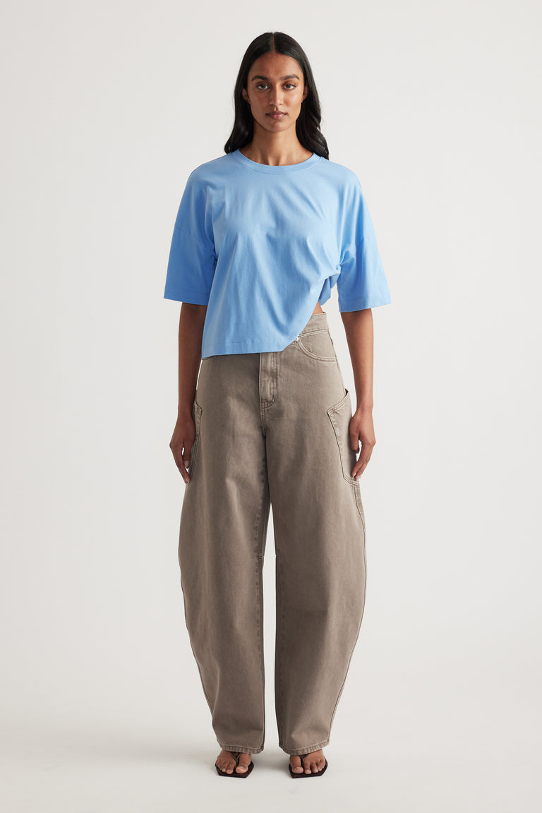 Woman wearing a blue cropped boxy tee with beige relaxed pants and black sandals