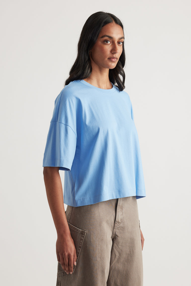 Woman wearing a light blue cropped boxy tee with relaxed sleeves and beige pants
