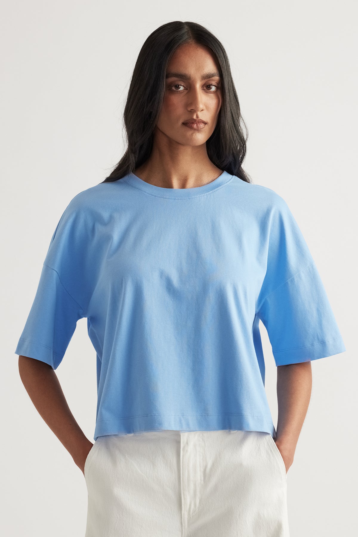 Woman wearing a relaxed blue cropped boxy tee with white pants