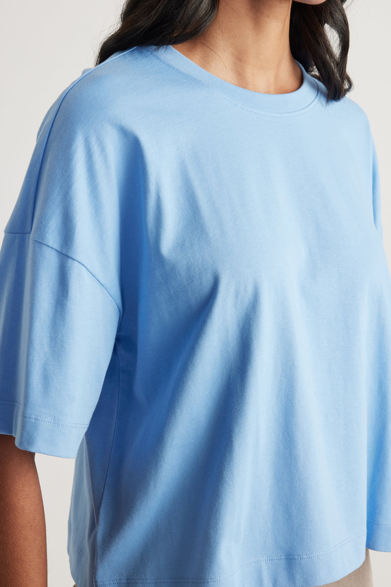 Woman wearing a light blue cropped boxy crew neck tee with relaxed short sleeves