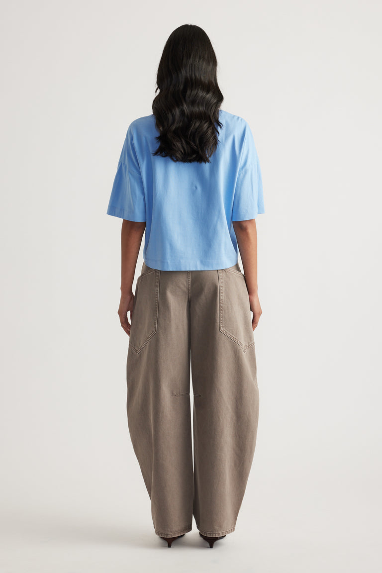 Back view of a woman wearing a light blue cropped tee with taupe wide leg pants
