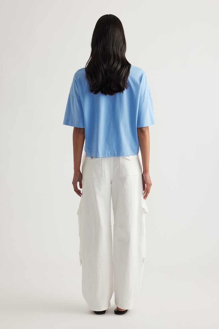 Back view of woman wearing a blue cropped tee with white wide leg cargo pants