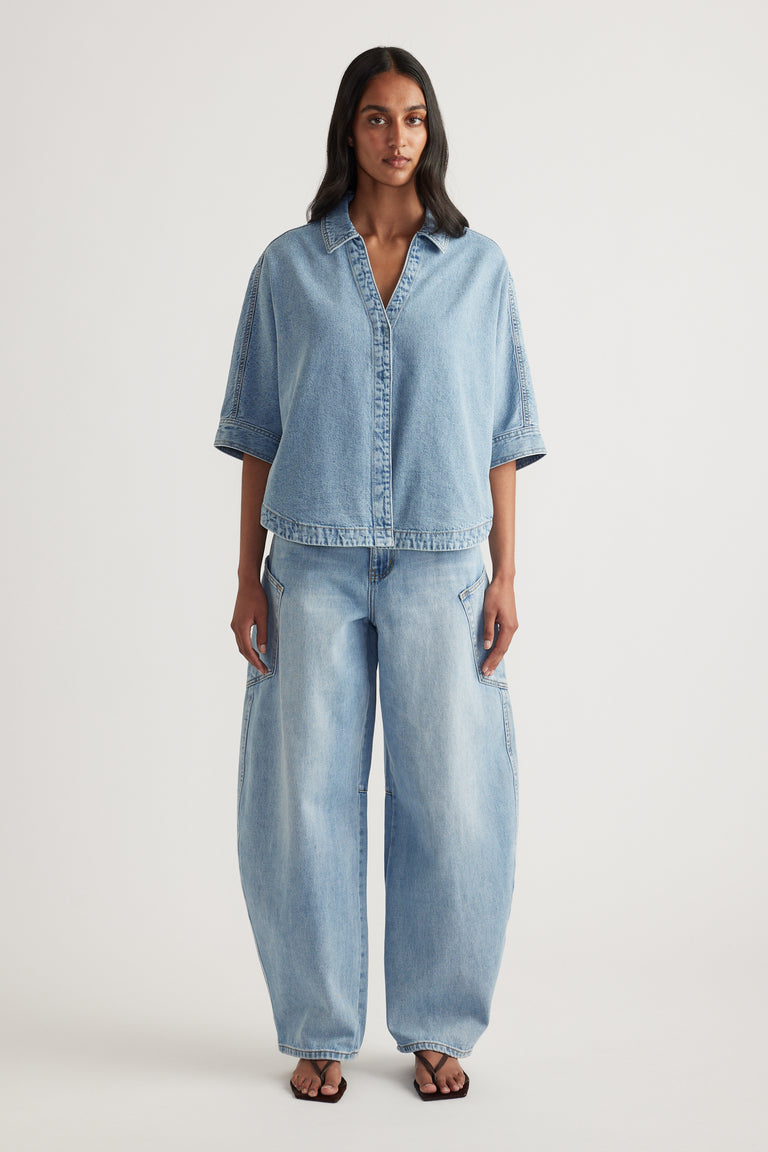 Woman wearing a light wash denim shirt with elbow-length sleeves and matching relaxed jeans