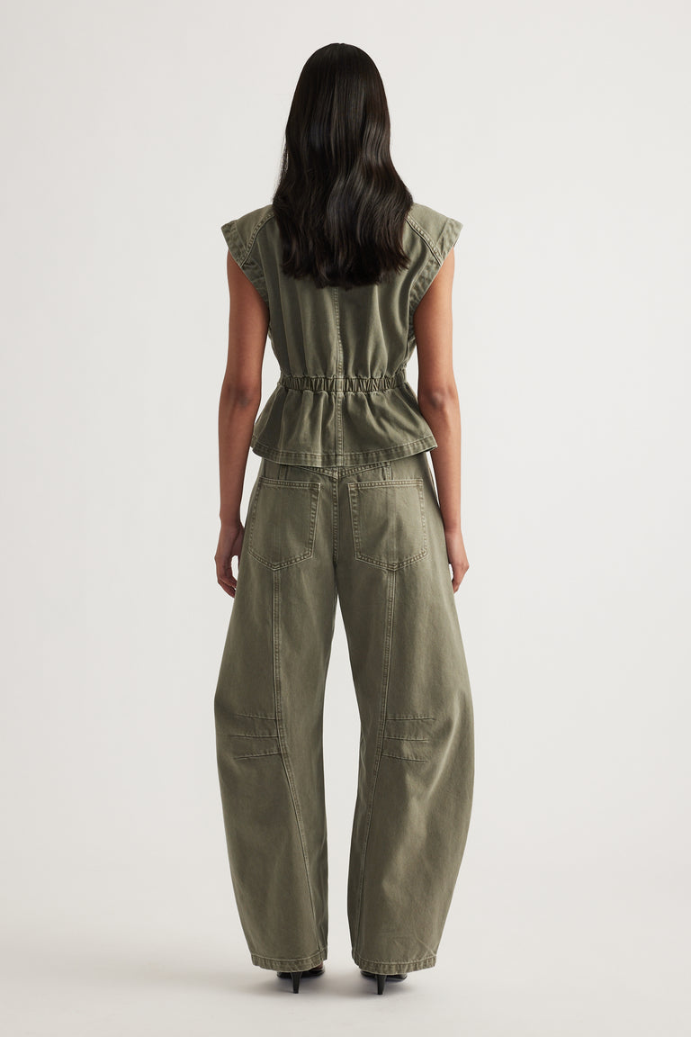 Woman viewed from behind wearing an olive denim cinched waist vest with wide-leg pants