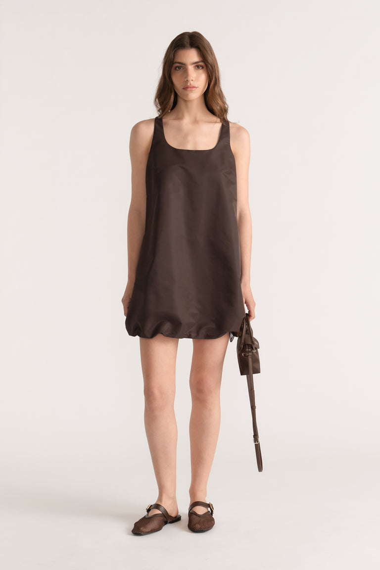 Model wearing a brown sleeveless scoop neck bubble mini dress with a drawcord hem and side pockets
