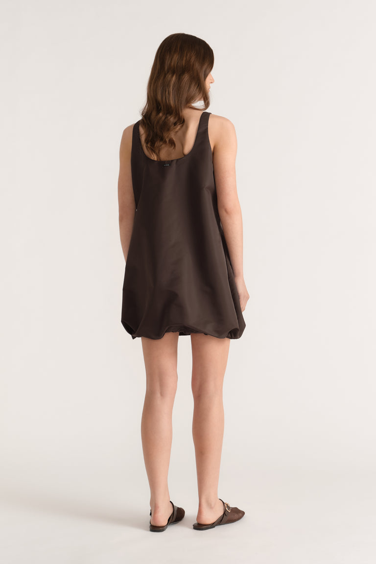 Woman viewed from behind in a dark brown sleeveless bubble mini dress with a scooped neckline