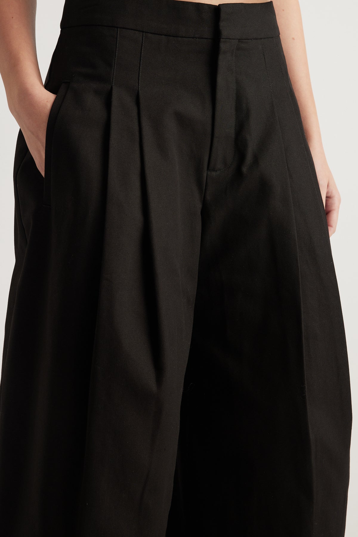 Woman wearing black high rise pleated wide leg pants with side pockets