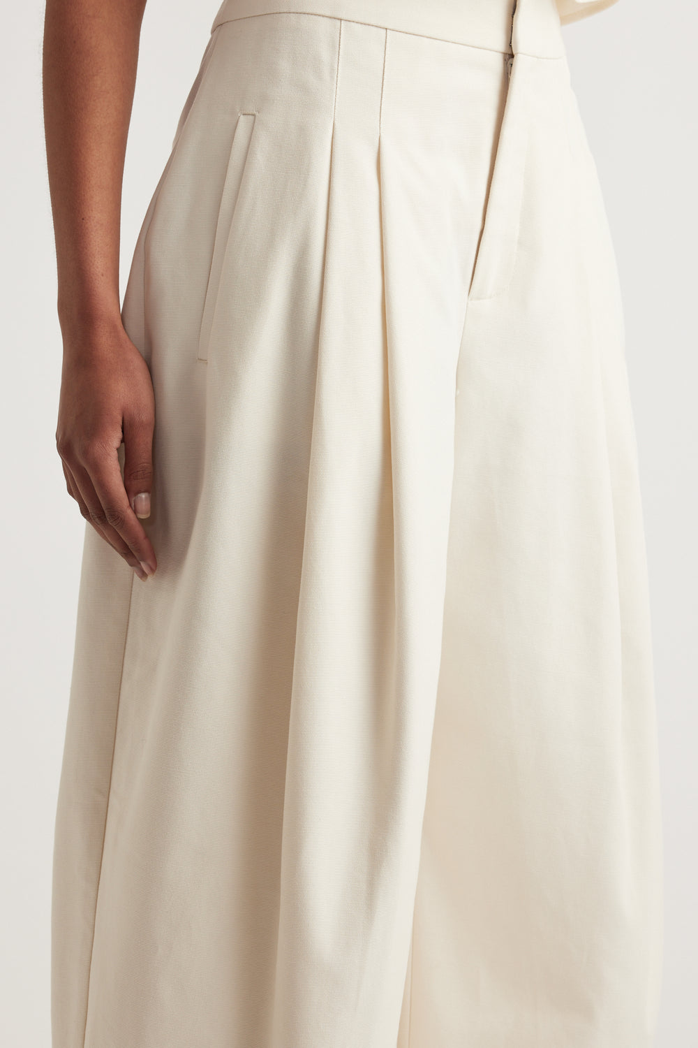 Close up of cream high rise pleated wide leg pants with tailored pockets