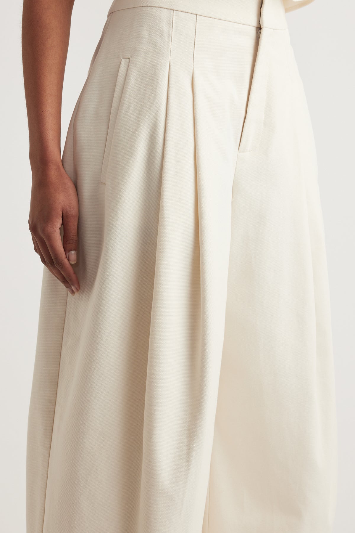 Close up of cream high rise pleated wide leg pants with tailored pockets