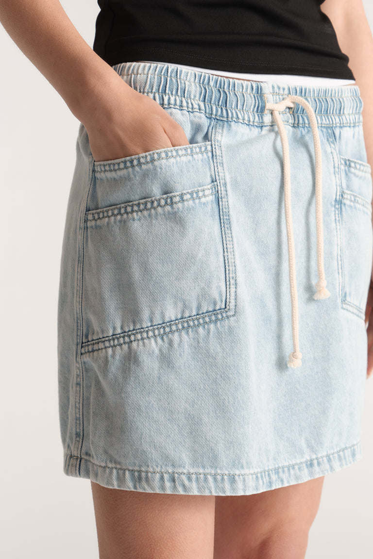 Light wash denim mini skirt with an elasticated drawstring waist and front patch pockets
