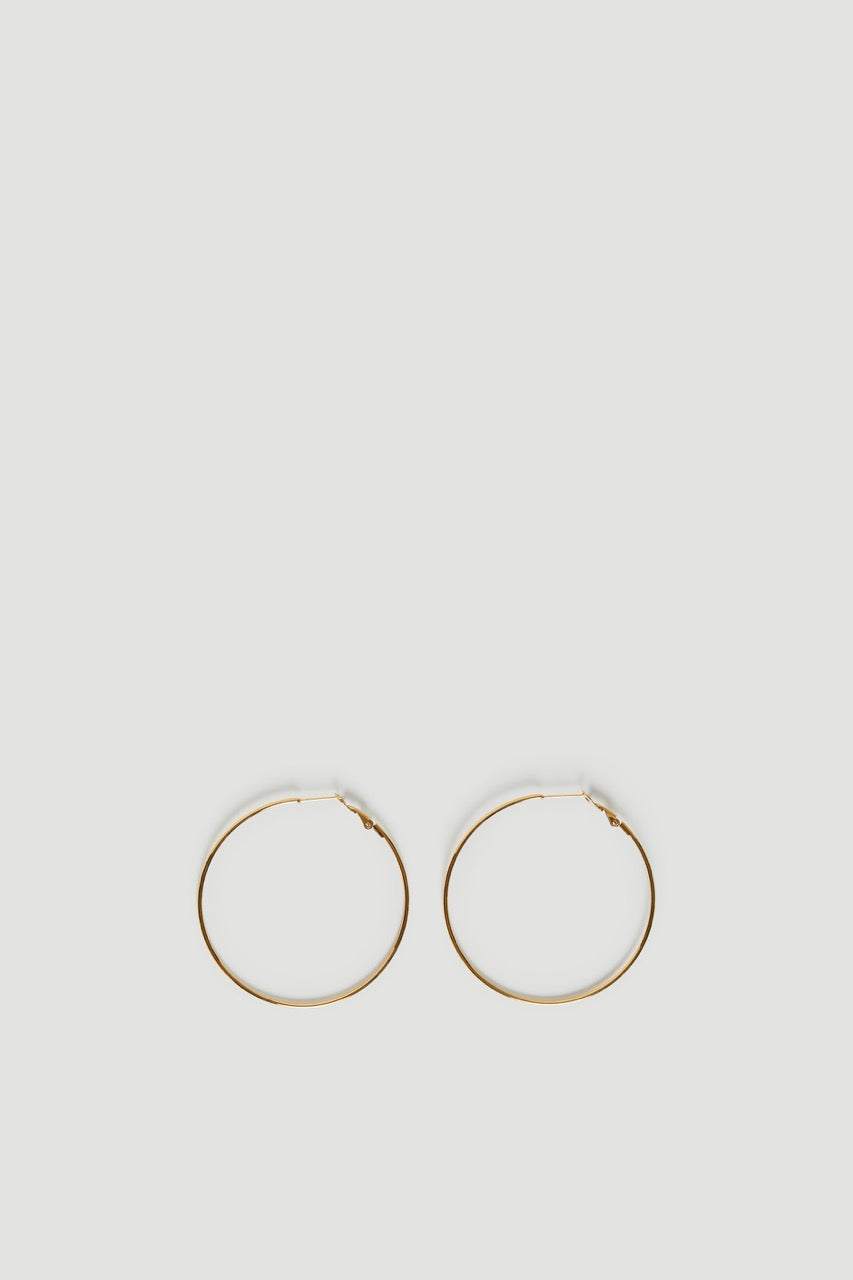 Pair of thin gold tone hoop earrings on a light background