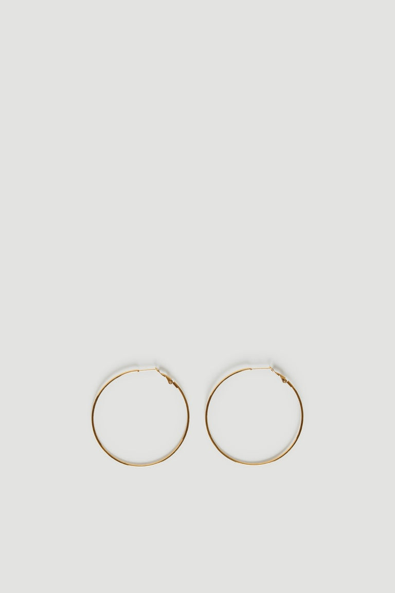 Pair of thin gold tone hoop earrings on a light background