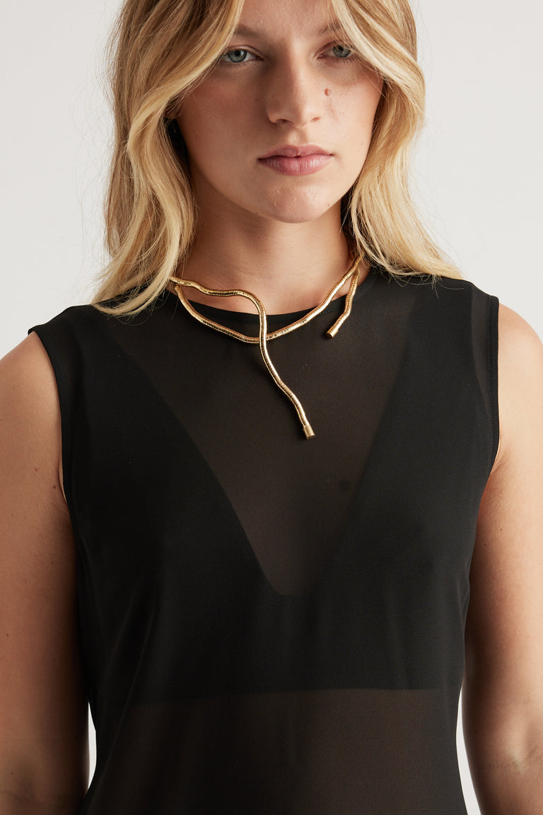 Close-up of woman wearing a sculptural gold wrap necklace paired with a sheer black sleeveless top for a chic look