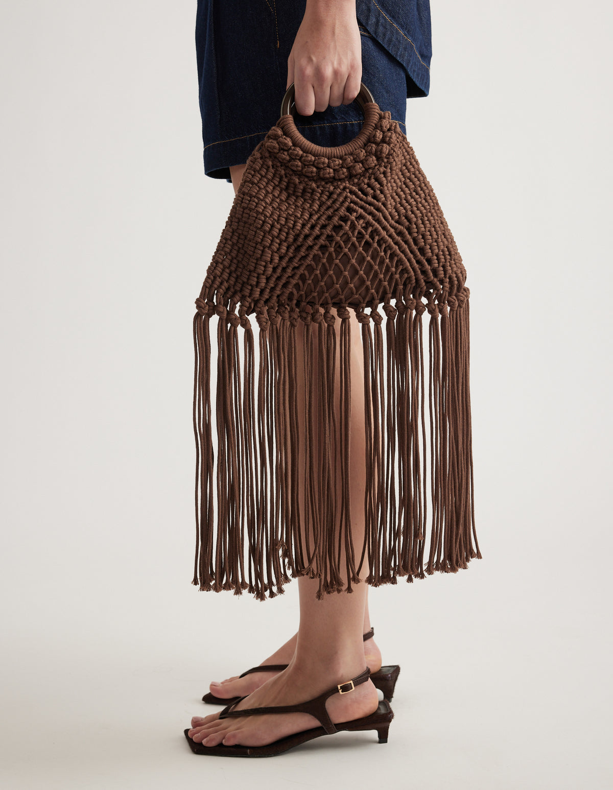 Brown crochet triangle bag with long fringe tassels and a braided top handle