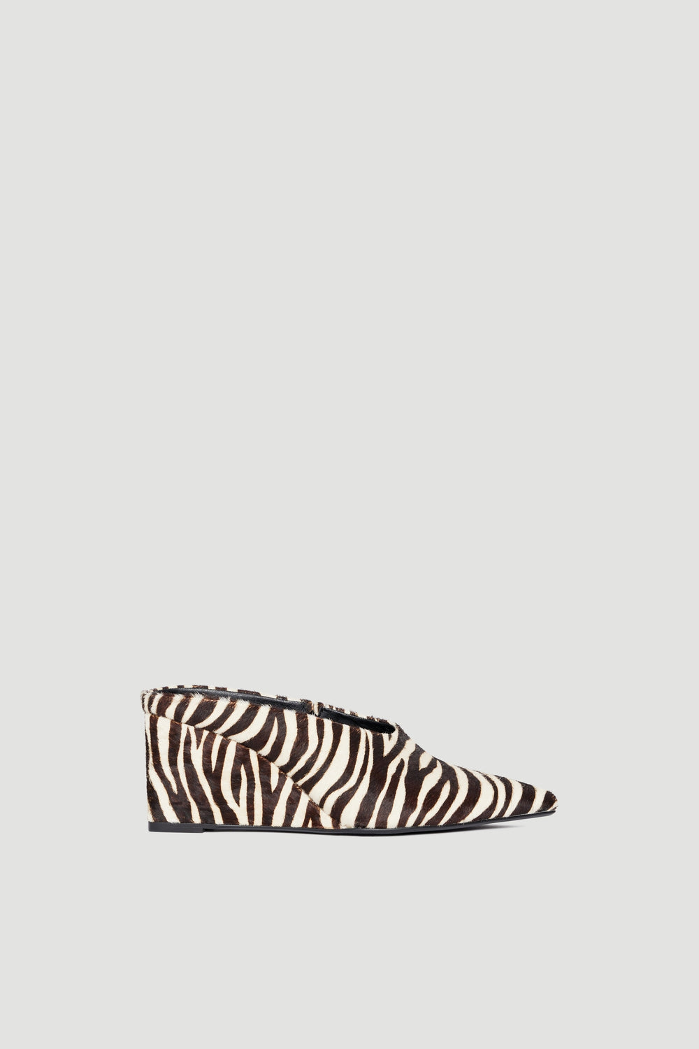 Pointed wedge slip-on shoe with open back and bold black and white zebra pony hair upper against light grey background