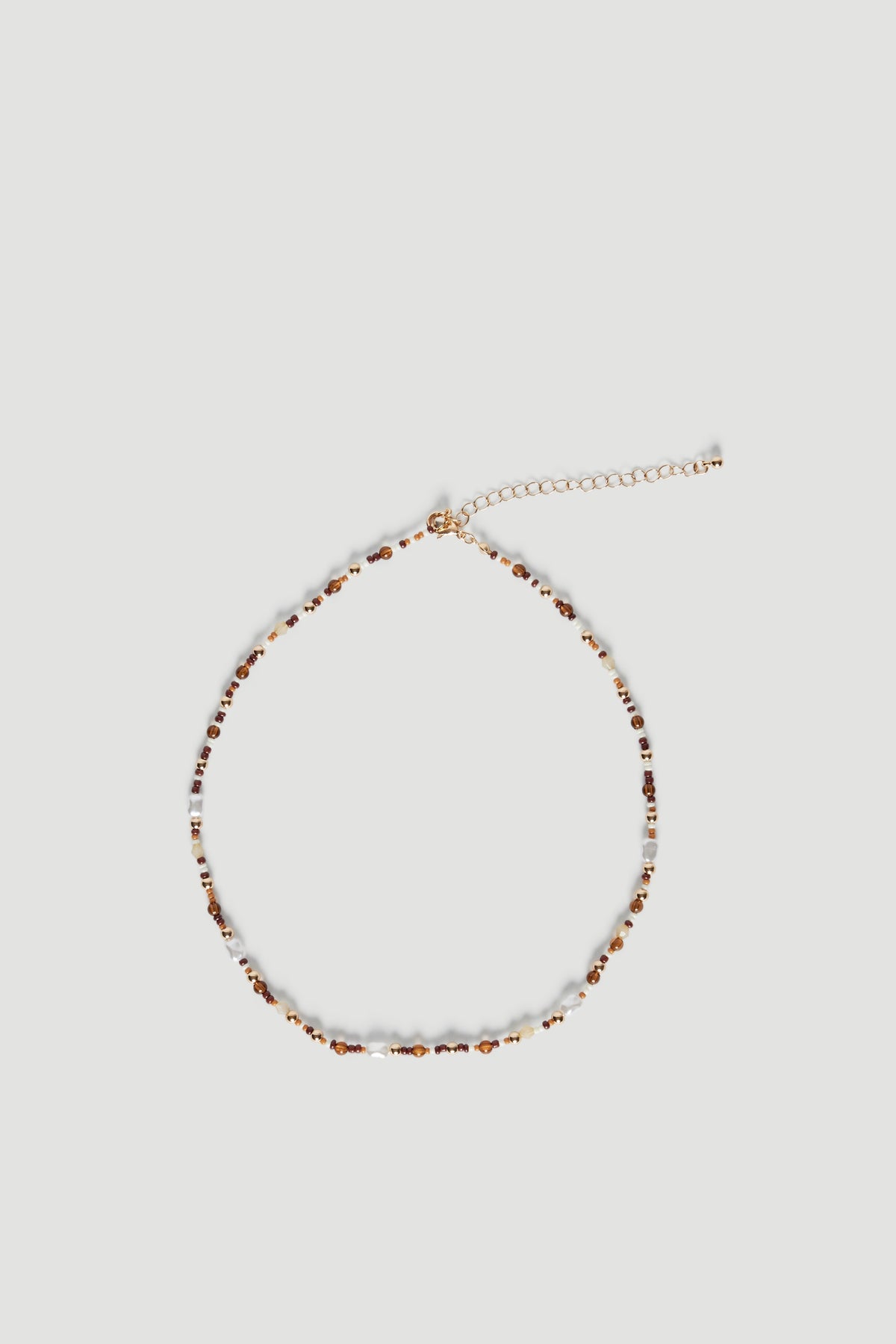 Delicate beaded necklace with natural-toned stones and faux pearls on a fine extension chain against light background