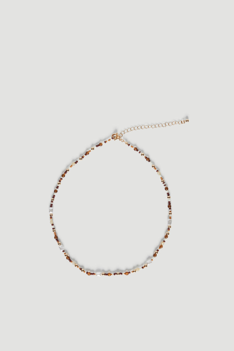 Delicate beaded necklace with natural-toned stones and faux pearls on a fine extension chain against light background