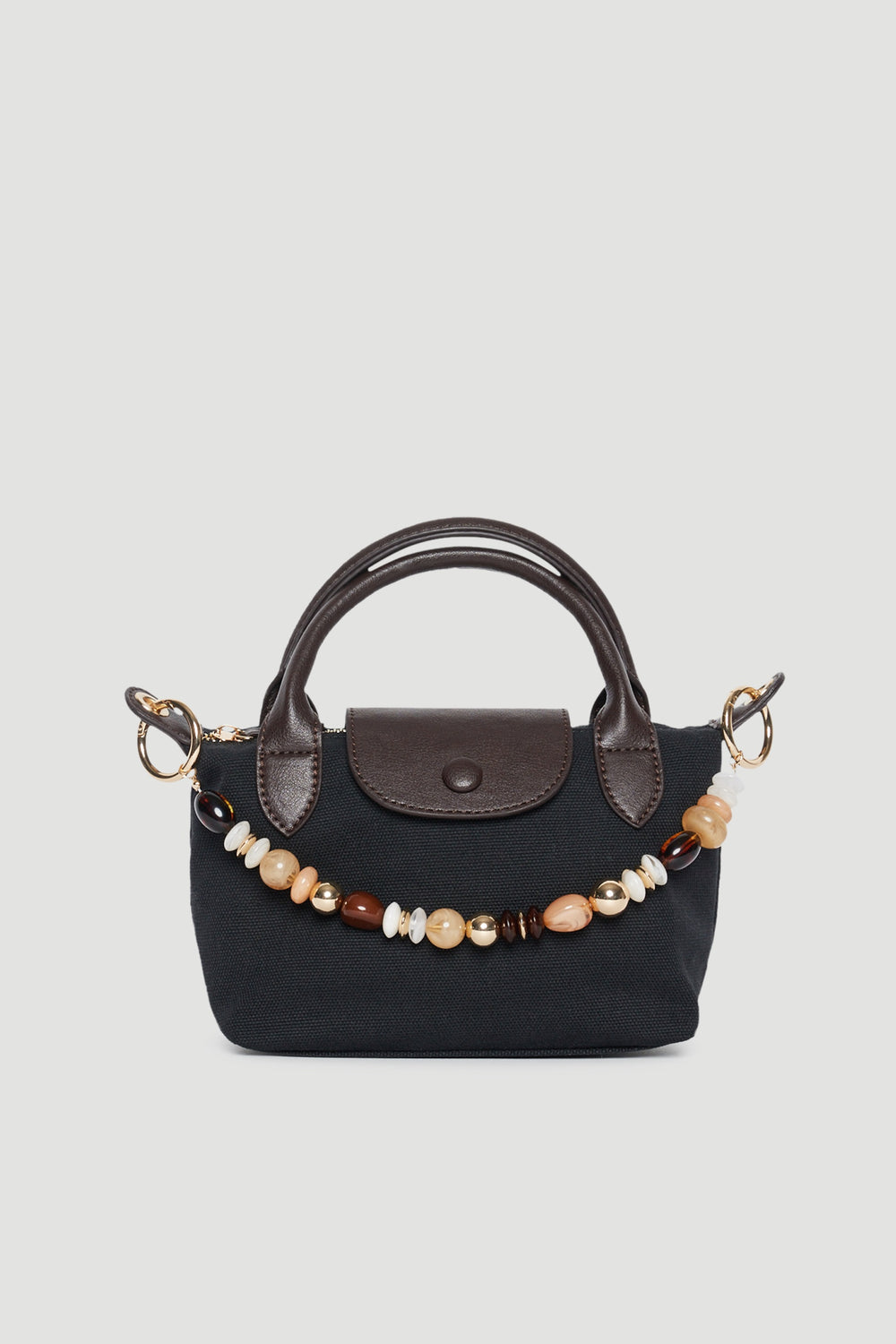 Black handbag featuring a beaded bag charm, brown trim and twin top handles