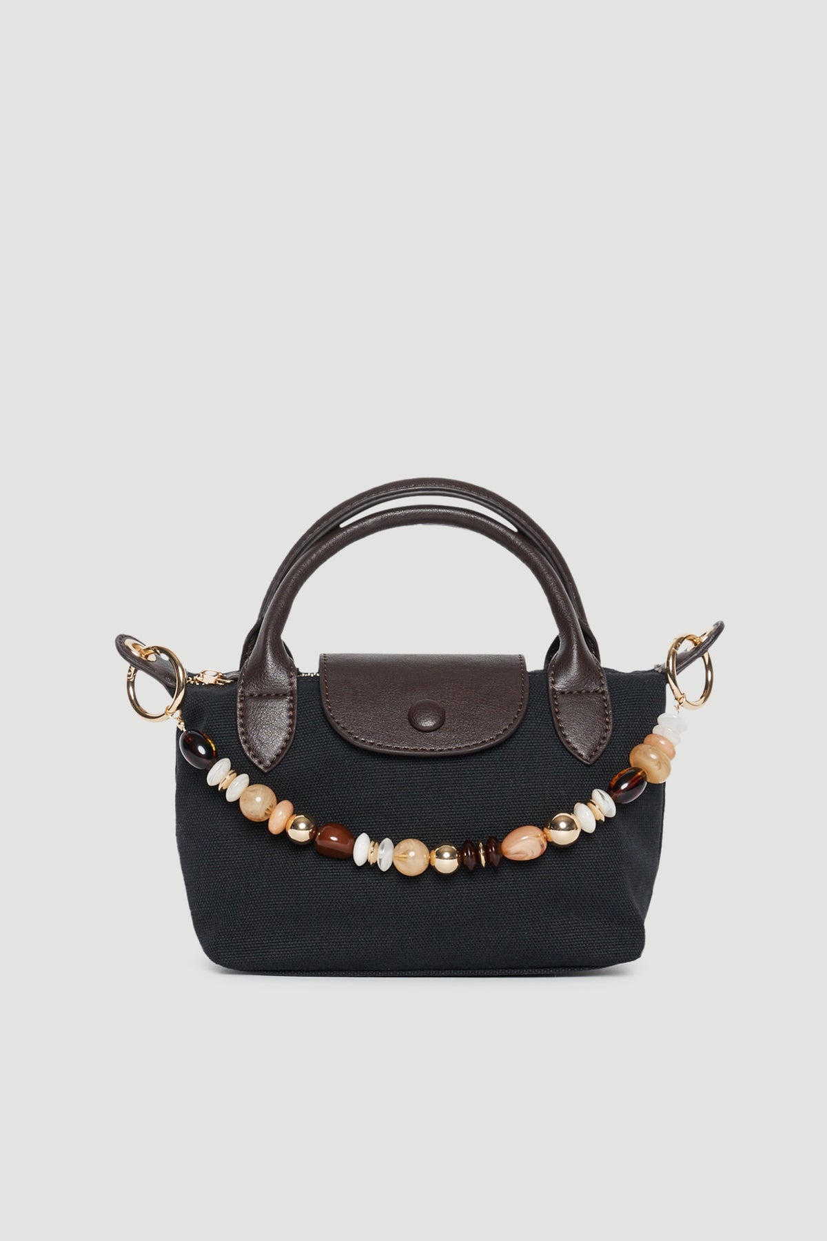 Black handbag featuring a beaded bag charm, brown trim and twin top handles