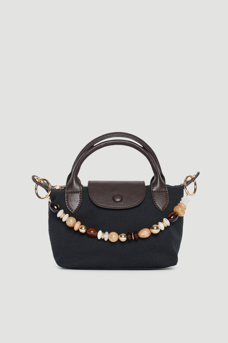 Black handbag featuring a beaded bag charm, brown trim and twin top handles