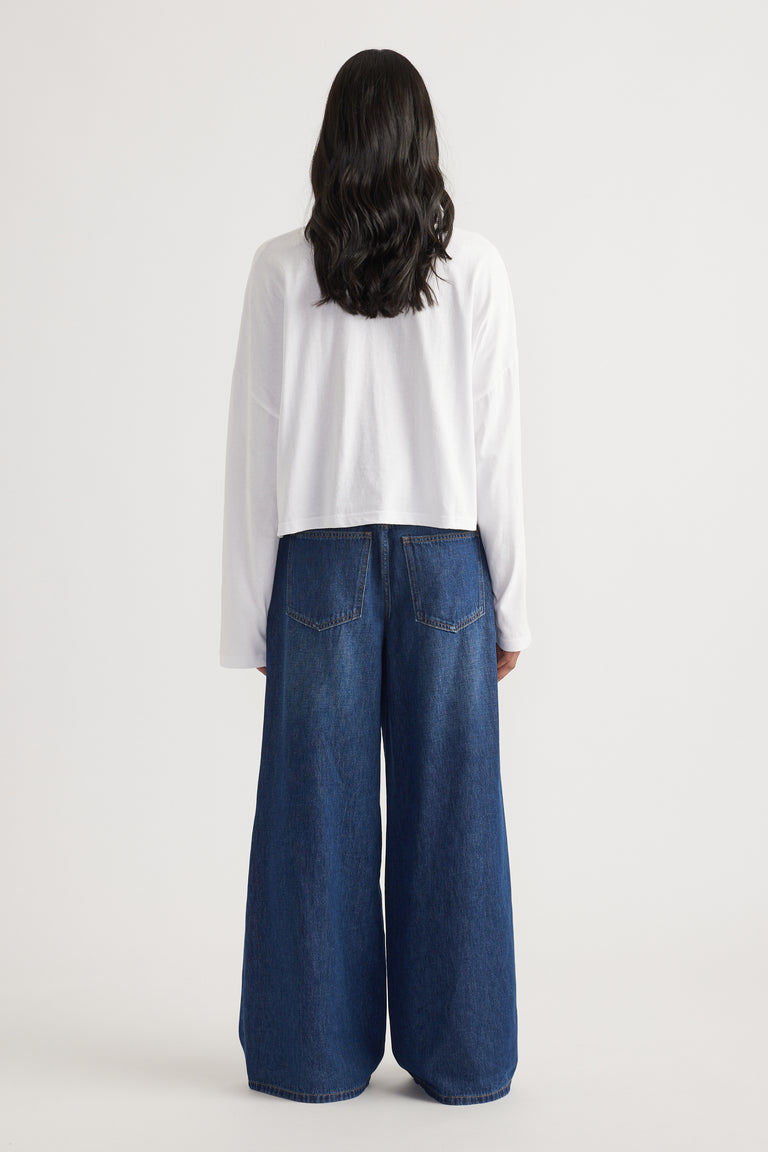 Rear view of woman wearing wide-leg dark blue denim jeans paired with a loose white long sleeve tee