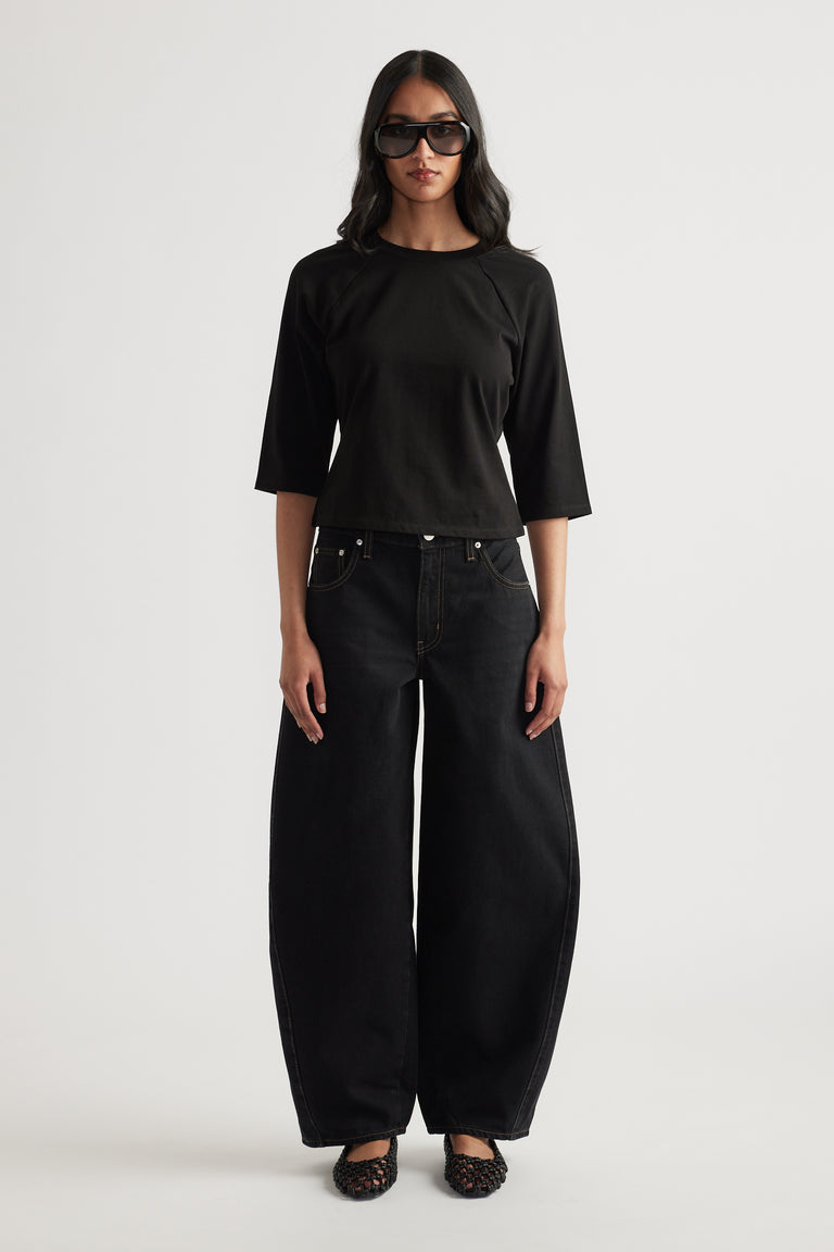 Woman wearing a black three quarter sleeve crew neck tee with wide leg black jeans and sunglasses