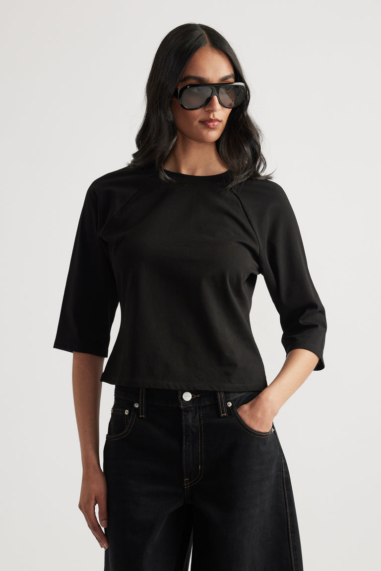 Woman wearing a fitted black three-quarter sleeve tee with black jeans and sunglasses