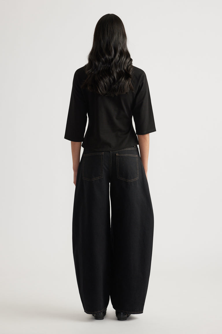 Woman viewed from behind wearing a black three-quarter sleeve tee with black wide-leg jeans
