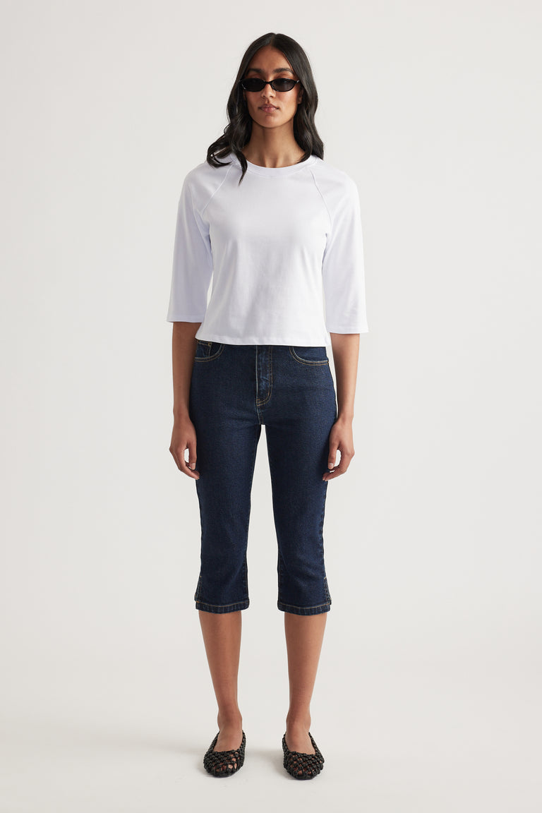 Woman wearing a white fitted three quarter sleeve crew neck tee with dark cropped jeans and sunglasses