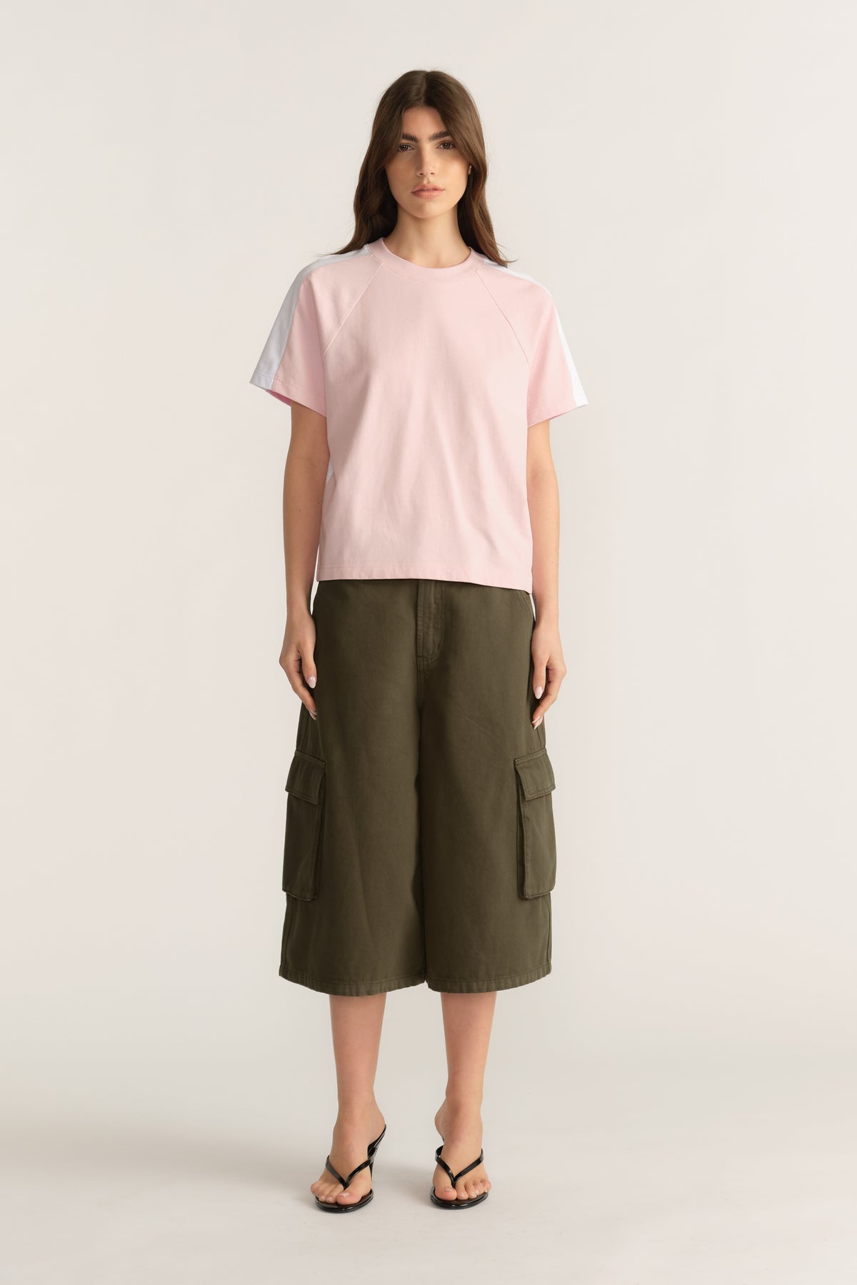 Woman wearing a pale pink short sleeve crew neck tee with olive cargo shorts and sandals