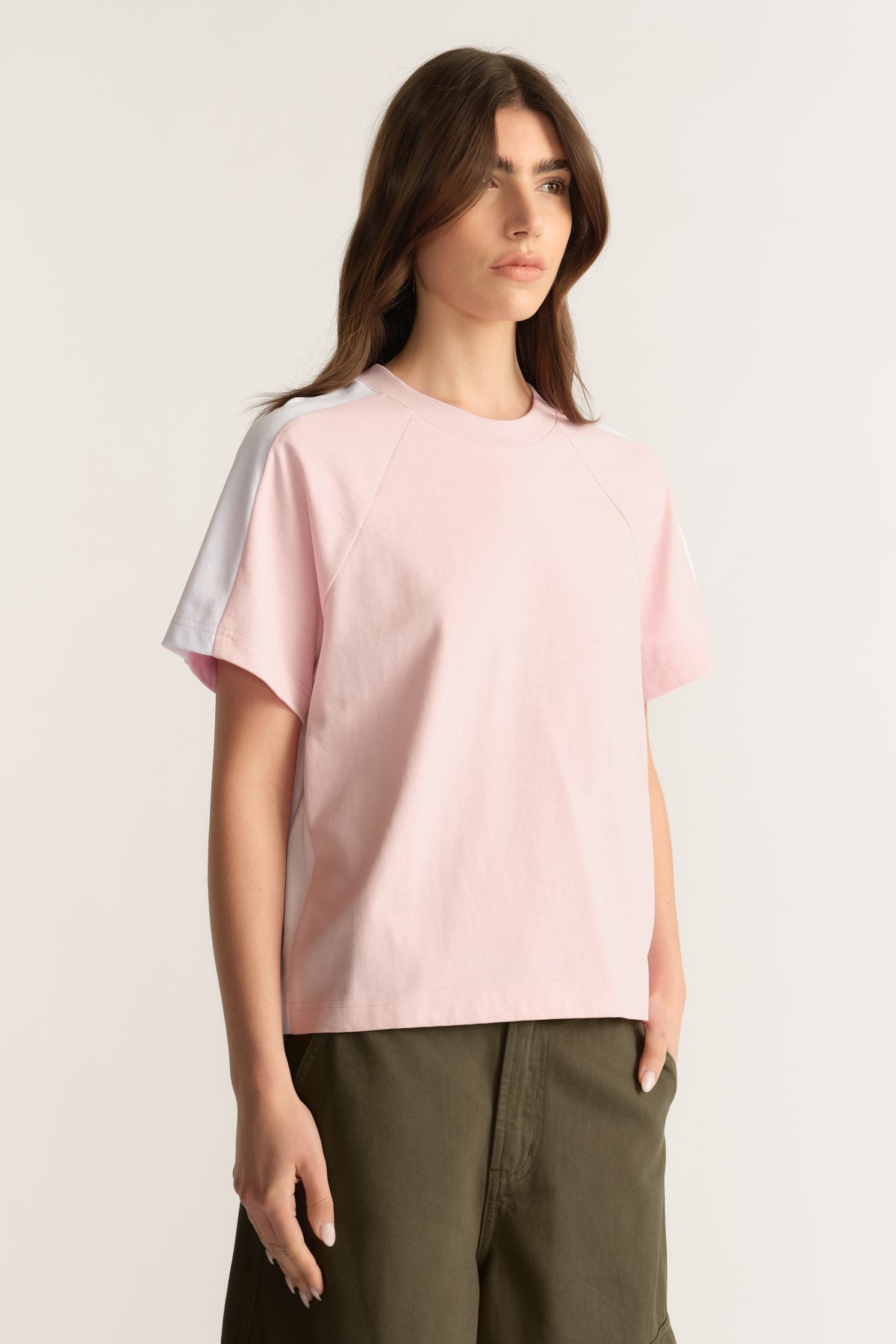 Woman wearing a pale pink relaxed fit round neck tee with short sleeves and olive pants