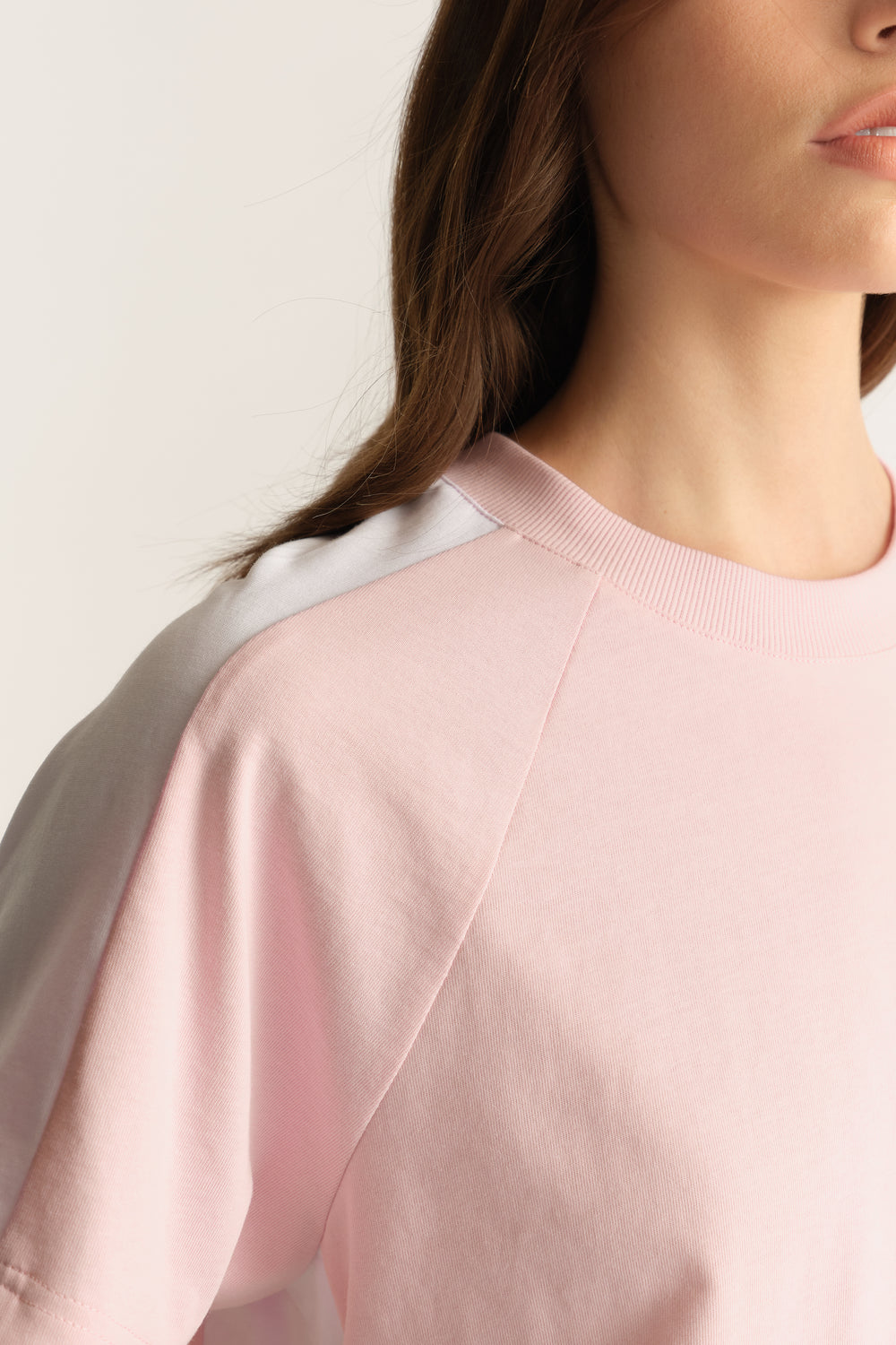 Close-up of a woman wearing a soft pink short sleeve tee with a round ribbed neckline