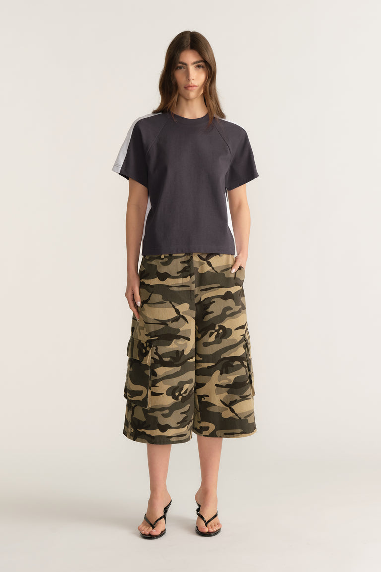 Woman wearing a charcoal short sleeve round neck tee with camouflage cargo shorts and flip flops