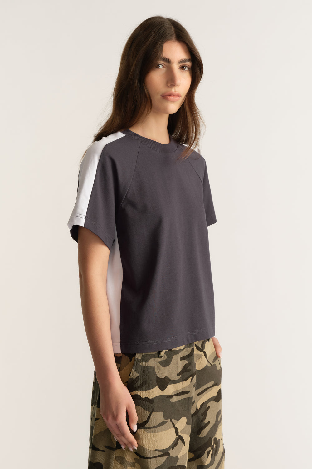 Woman wearing a charcoal ringer tee with white contrast sleeves and camouflage pants