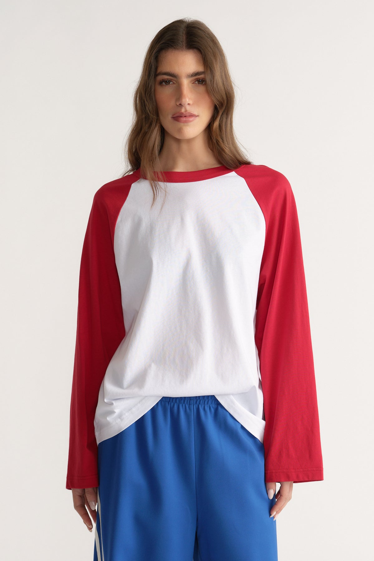 Woman wearing a white and red raglan long sleeve tee with blue pants