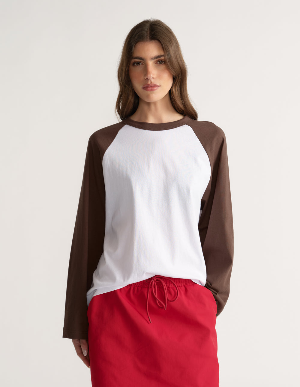 Woman wearing a white and brown raglan long sleeve tee with red drawstring pants