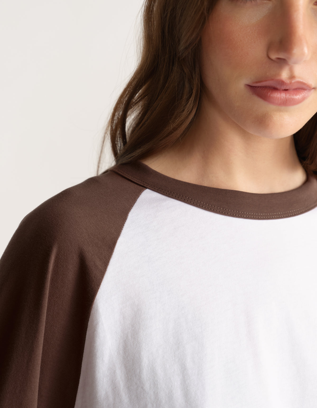 Woman wearing a white and brown contrast raglan sleeve crew neck tee