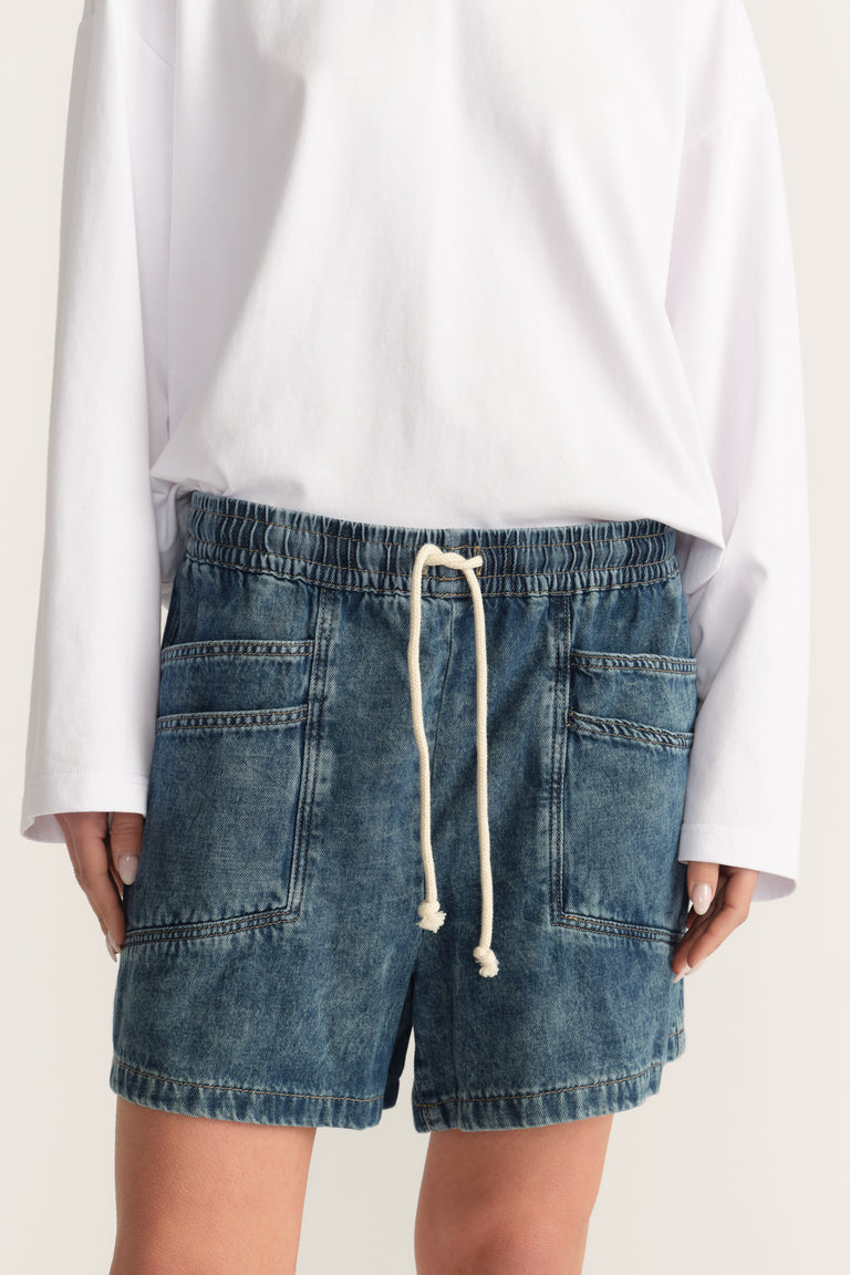 Woman wearing blue denim pull-on shorts with an elastic drawstring waist and utility pockets