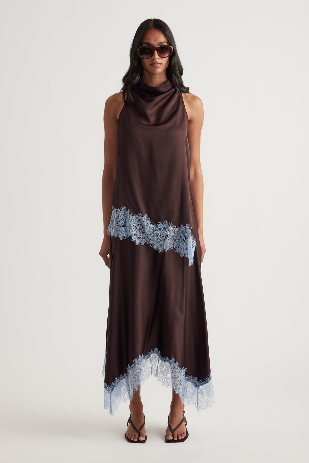 Woman wearing a chocolate brown satin top and lace trimmed handkerchief midi skirt with sunglasses and strappy sandals