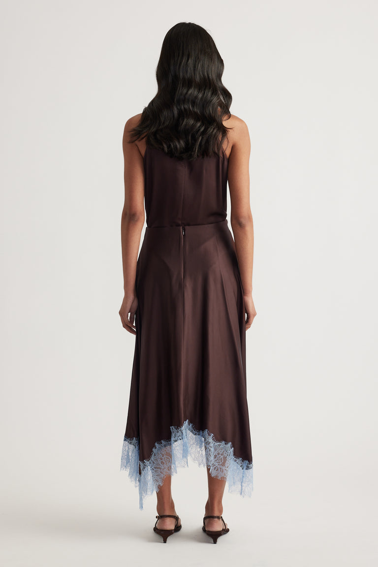 Back view of a woman wearing a chocolate satin midi skirt with blue lace trim and black heels
