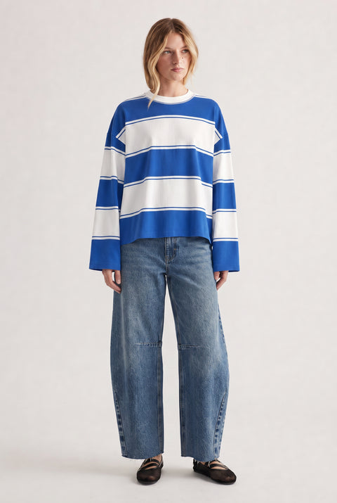 Woman wearing a relaxed long sleeve striped tee in blue and white paired with wide-leg denim jeans and black flats