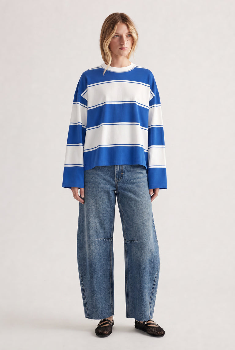 Woman wearing a relaxed long sleeve striped tee in blue and white paired with wide-leg denim jeans and black flats