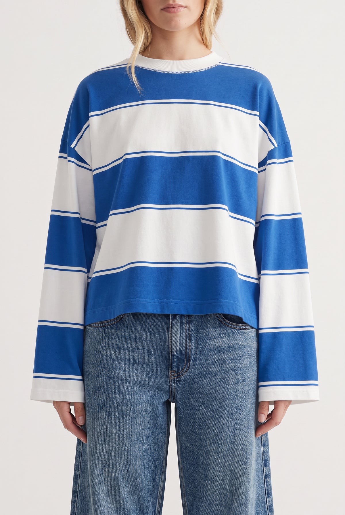 Casual long sleeve tee with bold blue and white wide stripes paired with relaxed fit blue denim jeans.