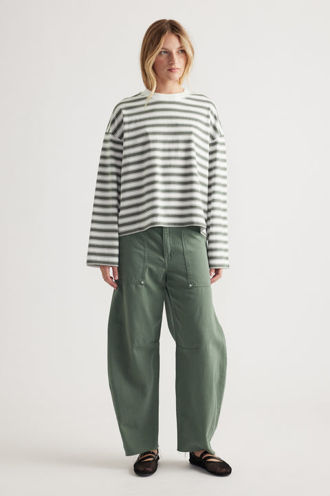 Woman wearing relaxed fit striped long sleeve tee with wide-leg olive green pants and black flats on plain background