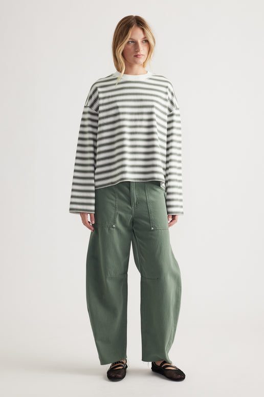 Woman wearing relaxed fit striped long sleeve tee with wide-leg olive green pants and black flats on plain background