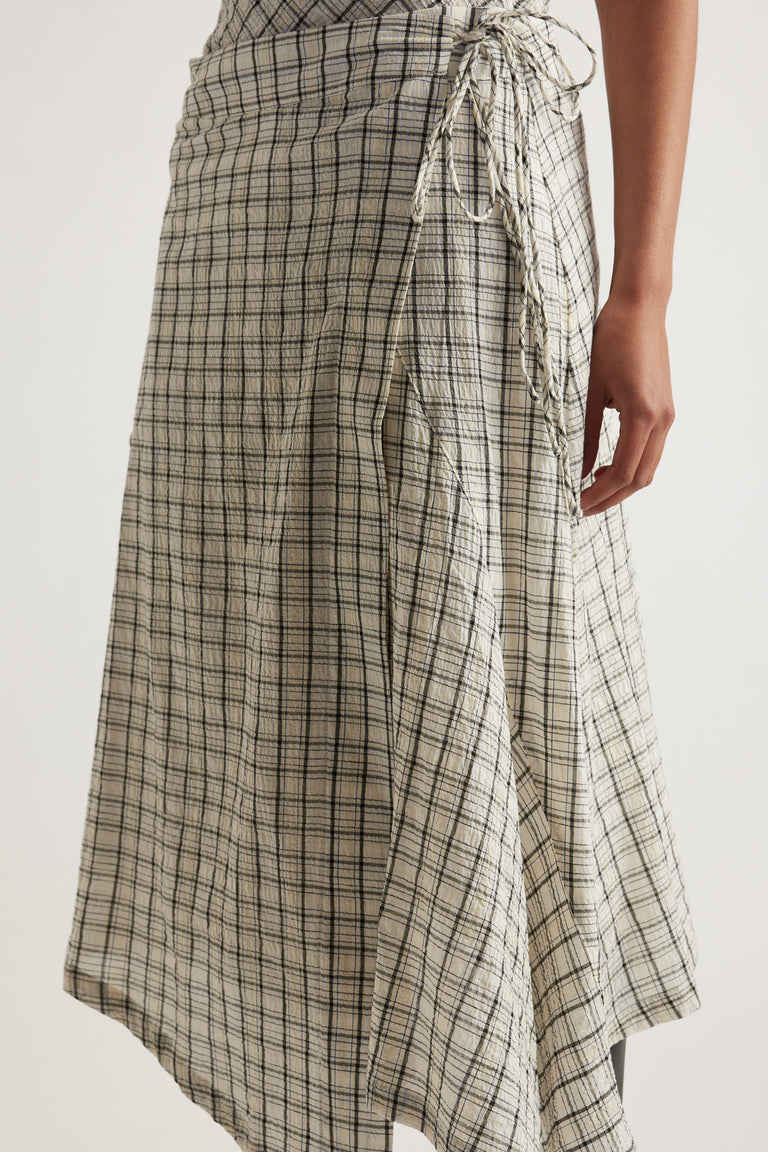 Woman wearing a beige checked wrap skirt with a tie waist and uneven hem