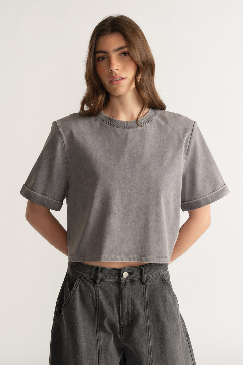 Model wearing a grey shoulder pad tee with dark high rise jeans