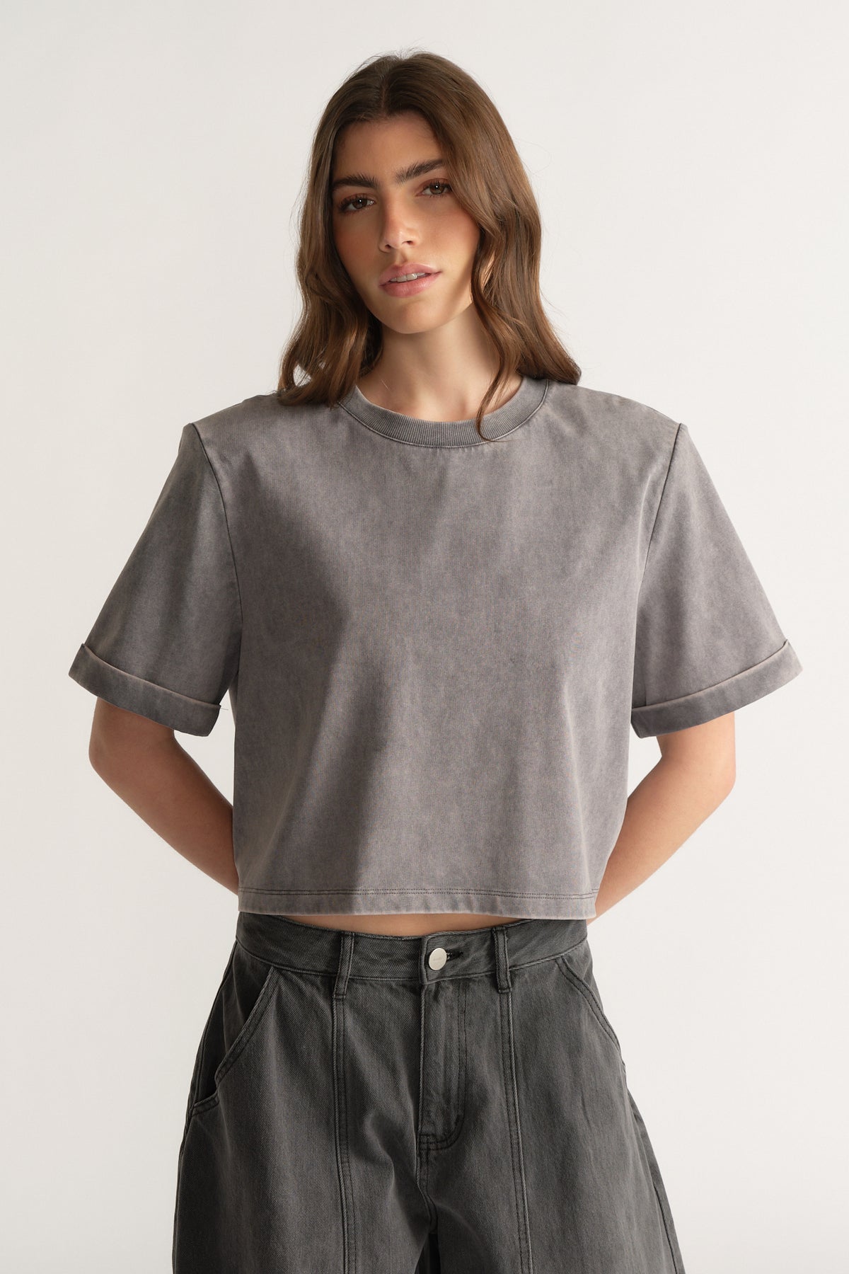 Model wearing a grey shoulder pad tee with dark high rise jeans